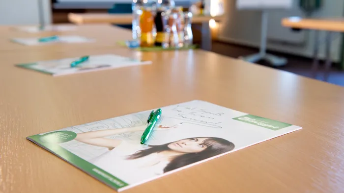 Konferenztisch mit Broschüren, grünen Stiften und Getränken für Seminarteilnehmer
